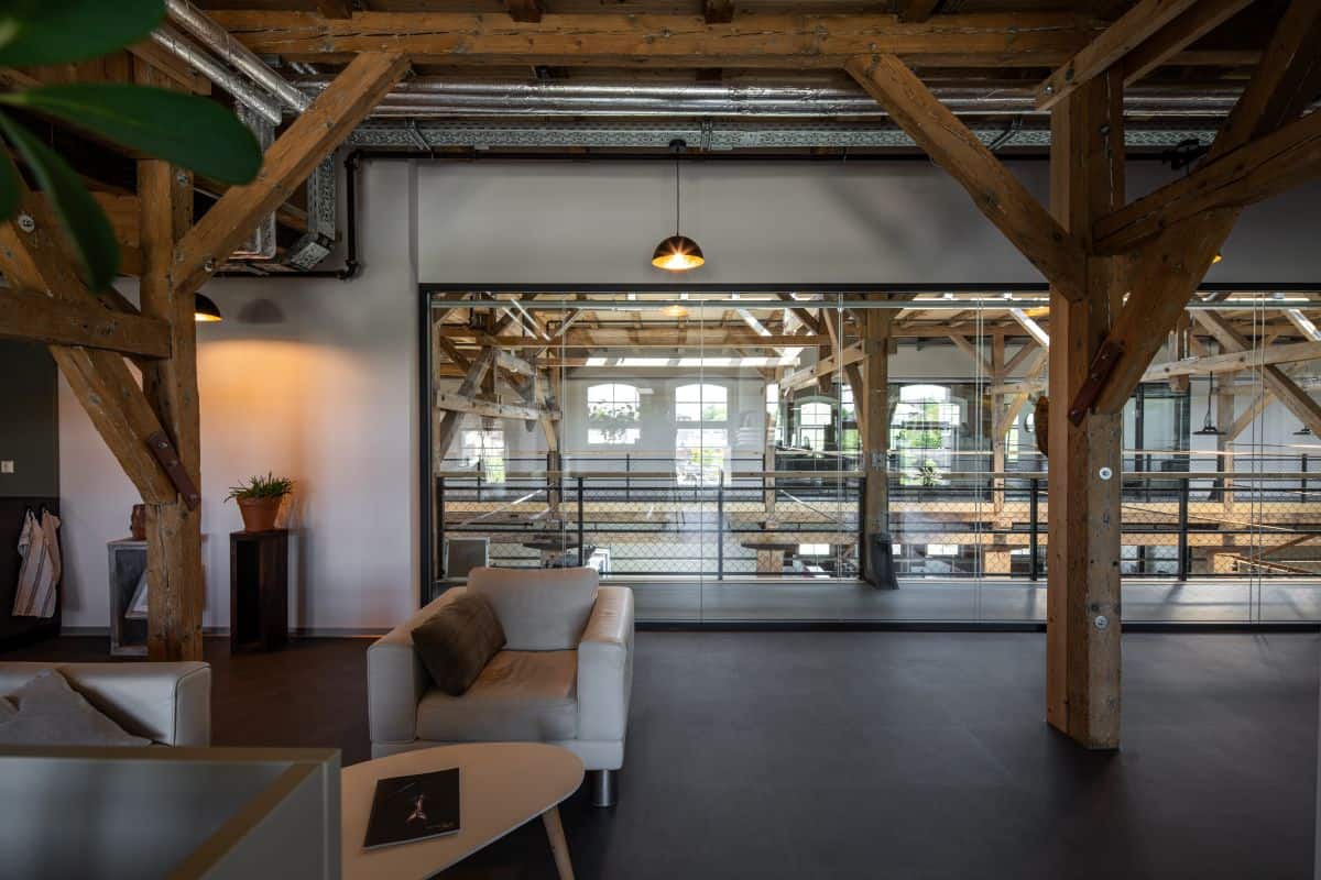Spacious modern office with wooden beams and large windows for natural light.